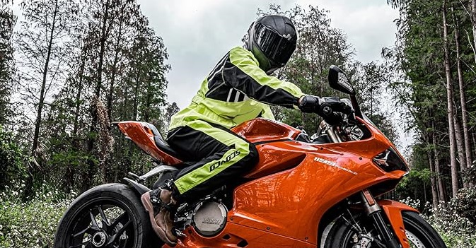 A motorcycle rider in retroreflective rain gear sits on a red Ducati Panagale sport bike